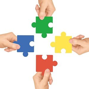 cooperation concept: hands holding jigsaw pieces over white background